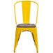 A yellow Flash Furniture metal restaurant chair with a wood seat and vertical slat back.