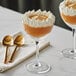 Two Acopa Nick and Nora cocktail glasses filled with dessert and topped with whipped cream and golden spoons.