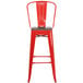 A red metal restaurant bar stool with a wooden seat and vertical slat back.