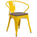 A yellow Flash Furniture metal chair with a wooden seat and back on a outdoor patio.