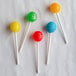 A group of lollipops on white paper sticks with different colors on them.