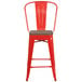 A red metal Flash Furniture restaurant bar stool with a wooden seat and vertical slat back.