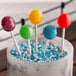 A bowl of blue and green lollipops on paper lollipop sticks.