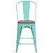 A mint green metal restaurant bar stool with a wood seat and vertical slat back.