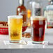 Two Acopa English Pub glasses filled with beer on a table.