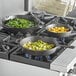 A group of Valor pre-seasoned cast iron skillets with food in them on a stove.