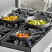 A group of Valor pre-seasoned cast iron skillets with vegetables cooking on a stove.