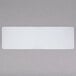 A white rectangular plastic folding table on a gray surface.