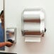 A woman in a blue shirt using the San Jamar Simplicity Essence Summit hands free paper towel dispenser.