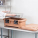 A woman loading a metal tray into a Cambro food pan carrier on a kitchen counter.