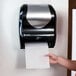 A woman using a San Jamar Hybrid Summit hands free paper towel dispenser.