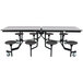 A rectangular black table with a black metal frame and T-molding edge with eight black round seats on a metal frame.