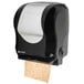 A black and silver San Jamar hands free paper towel dispenser.