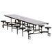 A long rectangular black table with metal legs and T-molding edge with black stools.