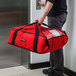A person holding a red Cambro Insulated Pizza Delivery GoBag.