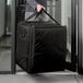 A person holding a large black Cambro pizza delivery bag.