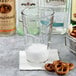 A person pouring water into an Anchor Hocking Swirl cooler glass with pretzels.