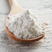 A wooden spoon full of Regal Arrowroot Powder on a table.