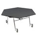 A hexagon shaped National Public Seating cafeteria table with a black frame and wheels.