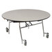 A National Public Seating round cafeteria table with a white and black edge on wheels.
