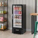 A black refrigerated glass door merchandiser with LED lighting, stocked with various beverages and food items.