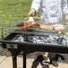 A person cooking meat on a grill using Jealous Devil hardwood lump charcoal.