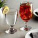 Two Acopa glass goblets filled with water and ice with lemon slices.