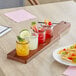 An Acopa mahogany flight paddle with rounded tasting glasses on a table in a cocktail bar.