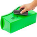 A hand holding a sponge on a green Storex plastic book bin.