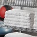 A metal rack with a stack of white Lavex bath towels.
