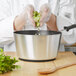 A person cooking food in a Vollrath Wear-Ever sauce pan with a black handle.