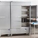 A man standing in front of a Beverage-Air stainless steel reach-in refrigerator.