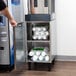 A person opening a metal cabinet with plastic bottles of water in it.