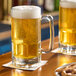 Two Anchor Hocking beer mugs filled with beer on a table.