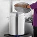 A person in a brown glove uses a Choice aluminum stock pot to cook.