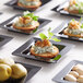 Fineline B6200-BK Tiny Temptations black plastic trays with appetizers on them.