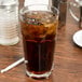 A Libbey Gibraltar iced tea glass filled with ice tea on a table with a salt shaker.