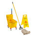 A yellow Lavex mop bucket with mop heads, a mop, and a wet floor sign.