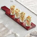 An Acopa mahogany wood tasting flight paddle with Barbary glasses filled with pasta on a table.