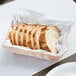 A Tablecraft beige rectangular woven rattan bread basket with sliced bread inside.