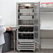 A person in a white coat holding a tray of trays standing in front of a Beverage-Air reach-in refrigerator.