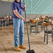A man holding a Carlisle black threaded fiberglass broom handle.