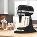 A black KitchenAid Artisan mixer on a wooden countertop.