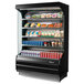 A Turbo Air black refrigerated air curtain merchandiser with food and drinks on shelves.