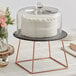 An Acopa slate and rose gold wire cake stand with a cake on it.