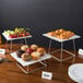 A table with a Acopa chrome wire riser set holding plates of food.