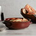 A bowl of Acopa Keystone chestnut stoneware onion soup with bread on a table.