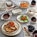 An Acopa Keystone stoneware onion soup crock on a table with plates and bowls of food.