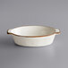 An Acopa Vanilla Bean stoneware oval casserole dish with brown trim.