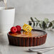 A white table with a dessert in an Acopa Keystone chestnut stoneware dish topped with raspberries and lemon.